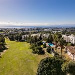 Vista aérea de una zona residencial con campo de golf y el mar al fondo en La Costa del Sol