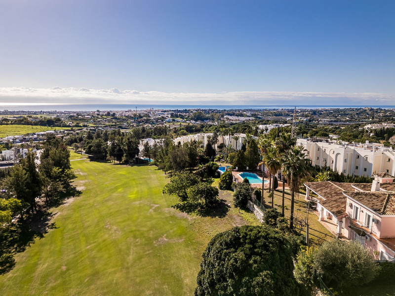 Vista aérea de una zona residencial con campo de golf y el mar al fondo en La Costa del Sol