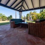 Terraza amueblada con sofás de mimbre y vistas al jardín en propiedad de La Costa del Sol