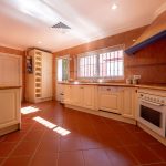 Cocina rústica con mobiliario blanco y encimeras de madera en villa de La Costa del Sol