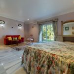 Vista del dormitorio principal desde la cama con decoración floral y acceso al jardín en villa de La Costa del Sol