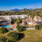 Vista aérea de villa con piscina y palmeras en urbanización de La Costa del Sol