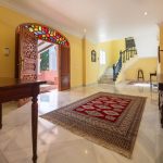 Recibidor con escalera y puertas talladas en madera con vitrales de colores en casa de La Costa del Sol