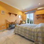 Dormitorio secundario con paredes naranjas, cama individual y vistas exteriores en propiedad de La Costa del Sol