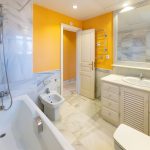 Baño completo con bañera, lavabo y paredes de mármol en casa de La Costa del Sol