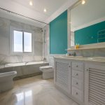Baño en suite con bañera, doble lavabo y pared verde en vivienda de La Costa del Sol