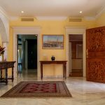 Recibidor con columnas de mármol, puertas talladas en madera y detalles artesanales en residencia de La Costa del Sol