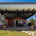 Porche cubierto con columnas y mobiliario de exterior en villa de La Costa del Sol